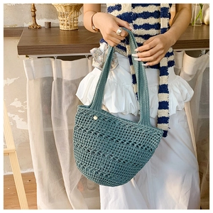 Detail of teal woven tote bag showing intricate hollow crochet texture and button closure