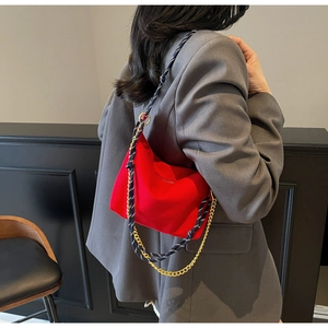 Detail of red nylon hobo bag showing blue woven rope and gold metal chain strap