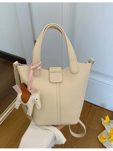 Chic cream leather bucket handbag with pony charm and adjustable shoulder strap