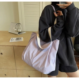 Detail of a large purple canvas tote bag with wide white shoulder straps for casual use