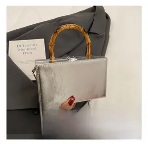 Detail showing the silver box bag texture and vintage bamboo handle with a chain