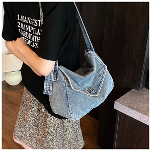 Dettaglio della borsa a tracolla in denim blu lavato con chiusura a scatto in metallo