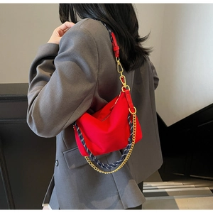 Detail view of red nylon hobo bag featuring woven rope strap and gold metal chain link