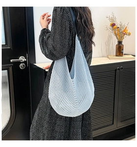 Detailed side view of light blue crochet hobo beach bag with slim black shoulder straps