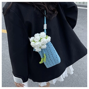 Detail of light blue hand-knitted mini crossbody bag with white flower bouquet decor
