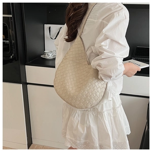 Détail de la texture en cuir tressé crème et du profil latéral arrondi du sac hobo chic
