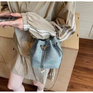 Close-up of gray-blue glitter bucket bag with silver butterfly clasp and pearl drawstring