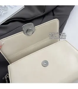Detail of cream crossbody bag featuring a secure magnetic snap closure and fine stitching