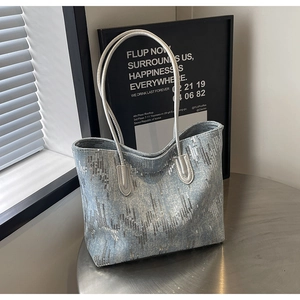 Detail of light blue denim tote bag with silver glitter stripes on a metal table