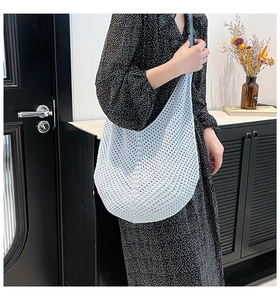 Close-up of light blue hollow-out crochet shoulder bag with intricate woven net texture