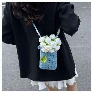 Detail of hand-crocheted blue knit bag with white floral accents and bead strap