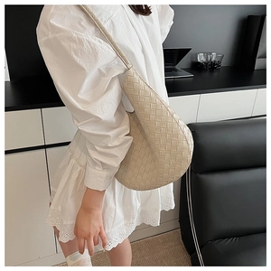 Détail du sac hobo tressé beige avec large bandoulière dans un décor moderne chic