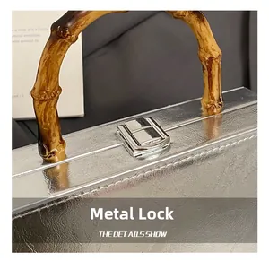 Macro detail of silver textured leather handbag featuring a dark bamboo handle and metal lock