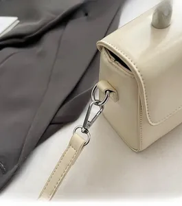 Detailed close-up of premium silver lobster clasp and leather strap on cream square bag