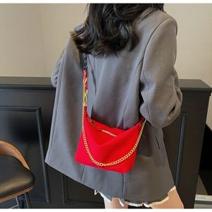 Detailed close-up of vibrant red nylon dumpling bag with gold chain and woven strap
