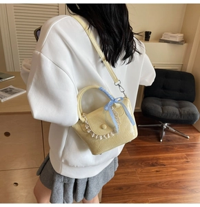 Détail du sac à main jaune avec bordure en dentelle, texture plissée et nœud à carreaux