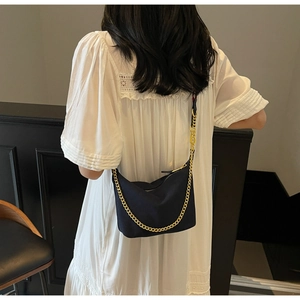 Detail of black nylon hobo bag with gold chain strap on a white dress model back view