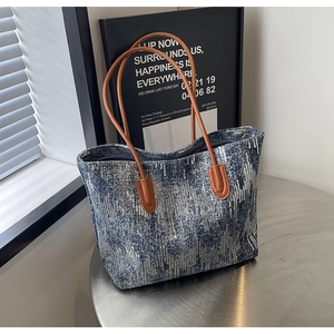 Detail of blue and white tweed tote bag with sequins, brown handles, and zipper