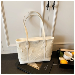 Detail shot of white tweed tote bag featuring delicate 3D floral accents and leather trim