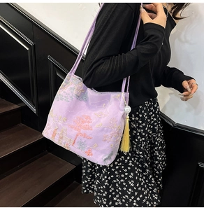 Detail of purple tote bag featuring heavy embroidery and yellow tassel with pearls
