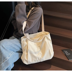 Spacious off-white canvas tote bag shown in a lifestyle scene with leather logo tag