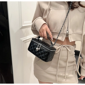 Detail of black quilted box bag with heart zippers and silver leather chain strap