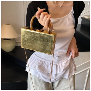 Detail of golden metallic box bag with vintage bamboo handle and chain strap