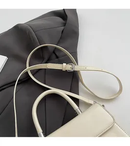 Detail view of cream shoulder bag with adjustable strap and silver metal buckle