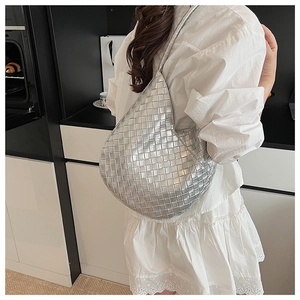 Sac hobo tressé argenté porté à l'épaule dans un décor intérieur minimaliste