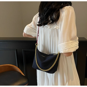 Detail view of black nylon hobo bag with chunky gold chain and red woven rope strap