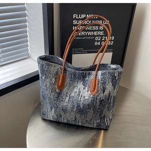 Close-up of blue sequin tote bag with wave texture and premium brown leather handles