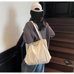 Minimalist large canvas tote bag with shoulder strap shown in a casual lifestyle setting
