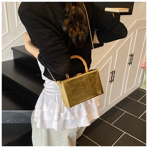 Detail of vintage square handbag featuring natural bamboo handle and gold chain strap