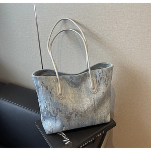 Detail of light blue denim tote bag with silver sequin waves and round handles