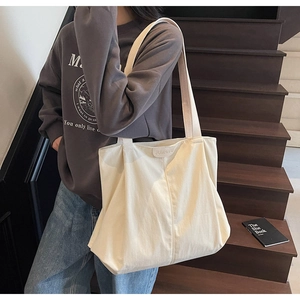 Detail shot of the cream canvas tote bag with JUMAITU leather logo and wide strap