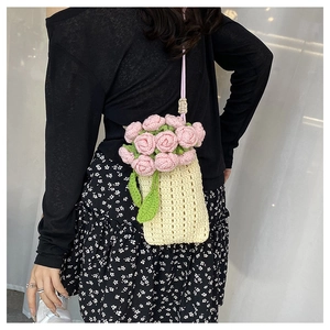 Detailed close-up of a handmade floral knit bucket bag with pink roses worn over a floral dress