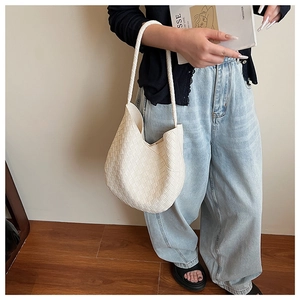 Détail d'un sac hobo tissé crème montrant la texture fine du cuir et son style minimaliste