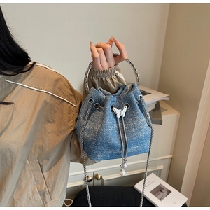 Detail of blue denim bucket bag with sparkling crystals and silver butterfly bow clasp