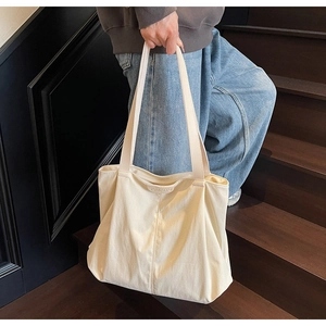 Close-up of the cream canvas tote bag showing high-density fabric and leather logo detail