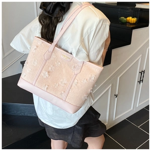 Detailed close-up of pink woven tote bag featuring 3D white floral appliques and gold logo