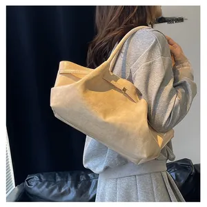 Detail van beige tas met krokodillenreliëf en goudkleurige hardware aan de schouderriem