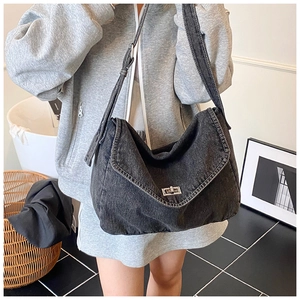 Dettaglio della borsa in denim nero con chiusura girevole in metallo e tracolla larga