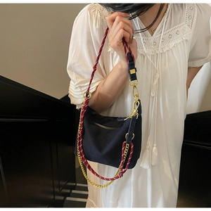 Detail of black nylon dumpling bag with red-white rope strap and gold metal chain
