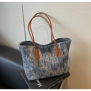 Detail of glittery blue gradient fabric and brown leather handles on a large tote bag