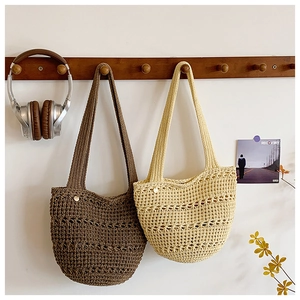 Detail of hand-woven hollow crochet tote bags in dark coffee and beige on wooden hooks