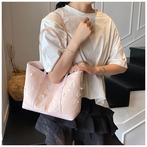 Detail of pink tote bag featuring 3D white floral appliques and leather handles