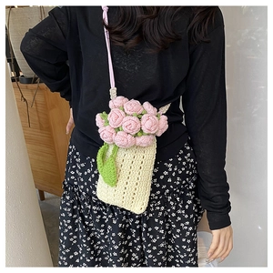 Detail of handmade crochet crossbody bag with pink and green floral knit embellishments