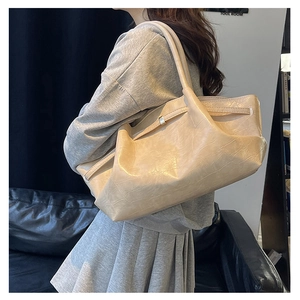 Zijaanzicht van beige geplooide kunstlederen tote tas getoond op een model