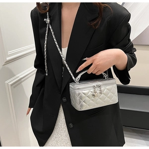 Silver quilted small square bag with metal handle and heart pendant on a model