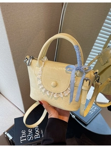 Sac seau jaune minimaliste avec bordure en dentelle et noeud bleu en vue miroir à la main